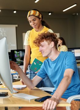 Students Using Computer Side View Side view portrait of two young students using computer together in modern school classroom