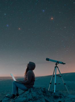 woman sitting in the desert with a laptop next to a telescope at night watching the starry sky, astronomy and stargazing concept woman sitting in the desert with a laptop next to a telescope at night watching the starry sky, astronomy and stargazing concept